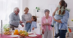 Happy big family gathering in living room at home together on holiday for a dinner. Parents, grandparents and children enjoying family dinner. Celebration and generations concept. 4k video.