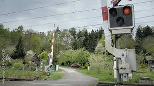Railroad crossing with railway gate that close. Level crossing occurs where railway barrier line is intersected by road or path on one level. Type of at-grade intersection. Static day stabilized shot.