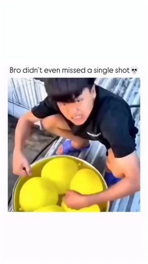KNOWLEDGE on Instagram: "The video captures a playful water fight or game, likely taking place on a patio or rooftop, centered around a man with a large basin of water balloons. The video begins with a close-up of a young man crouching over a large yellow basin filled with bright yellow water balloons. He is wearing a dark t-shirt and shorts, with a look of intense concentration or mischievousness on his face. The camera then quickly switches to a high-angle shot, showing a large, shallow pool o