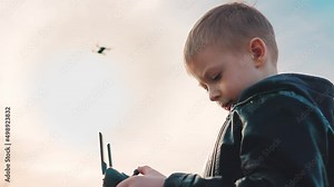 Happy boy plays with a drone in nature. Child controls the drone using a remote control.