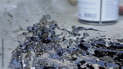 Worker spreads bituminous waterproofing putty on rough concrete or sand cement surface. Sticky viscous putty creates waterproof barrier to protect buildings from water. Structure moisture resistance