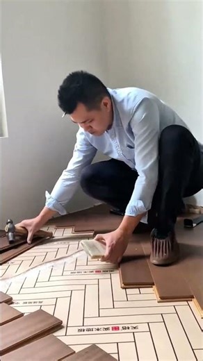 installing wooden floor panels in a herringbone pattern and securing them with a hammer and block