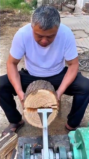 splitting large log using mechanical wood splitter to create firewood pieces for fuel preparation