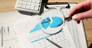 Analyst holding magnifying glass on graphic analytic chart on paper