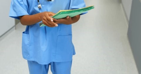 clip-3999358779-nurse-walking-ward-corridor-scanning-patient-folders