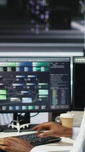 Vertical Data center admin using artificial intelligence neural network models to configure hardware. Man works on AI programming language in server room, optimizing system functionality, camera B