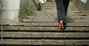close-up of women legs in trousers and high-heeled shoes climb up the stairs