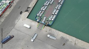 top view truck loading into a car carrier ship. Car ferry leaving docks fully loaded.