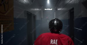Walking behind hockey player down dark ominous hockey arena corridor passing through pools of light, 4K