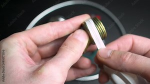 Plumber putting seal tape on a thread of a plumbing fitting