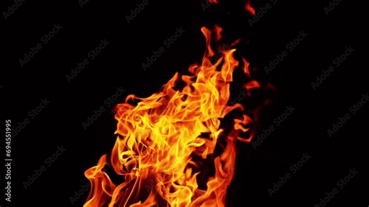 Beautiful fire flames moving in the darkness. Multiple sparks fly up and smoke rises behind. Close up.