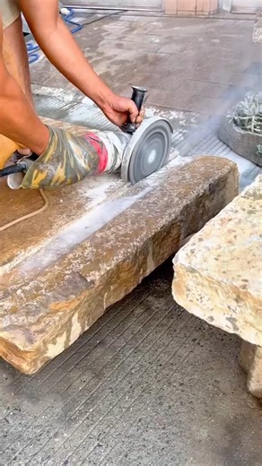 Skilled worker carefully grinding a large stone block to achieve a smooth surface