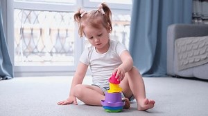 cute funny little baby girl build Colored cubes pyramid toy. kid playing on floor.Happy family. Puzzle game in the hands of children. Teaching children