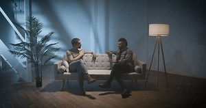 Two men on a couch interview scene, talking and sharing stories, podcast concept. High quality 4k footage