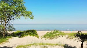 Zoom in view typical Baltic sea coast landscape beach view in Lithuania. Blue sky with no clouds, small waves in the sea and sand dunes partially overgrown with sedge grass