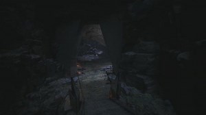 Mysterious Cave Entrance with Flickering Torchlight in the Darkness