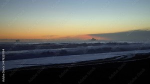 Stunning left panning shot of a peaceful sunset at the famous Ruby Beach in Forks, Washington with small waves and a small rock formation on a summer evening.