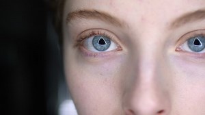 Close up of blue female eyes with triangle reflection in pupils looking at camera