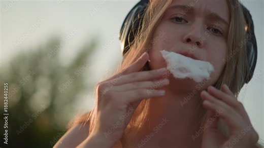 white girl eating cotton candy closeup, playful foodie at fairground, sugar moustache, fingers pulling fluffy treat, candid snacking action, warm sunset light, influencer style casual