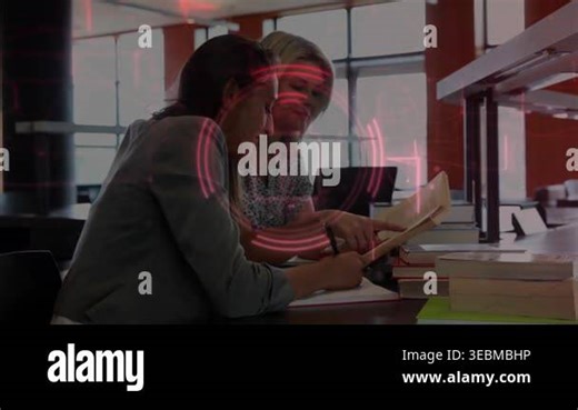 Two women studying for exam at table, red lock graphic appearing over pair while taking notes. Desk, books, notebook, laptop, collaboration, library, study Stock Video Footage - Alamy