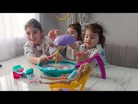 The sisters are swimming and playing with their Barbie and Chelsea dolls in the pool.
