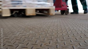Loading goods on a forklift pallet truck in a retail or wholesale warehouse. Logistics of distribution of products or humanitarian aid. Moving loaded warehouse trolley. Shooting video from the ground.
