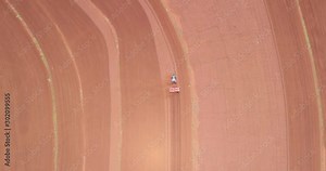 Aerial view of tractor with mounted seeder performing direct seeding of crops on plowed agricultural field. Farmer is using farming machinery for planting process, Brazilian farm. 4K.