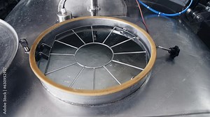 Modern machinery is producing cheese on the industrial line. Industrial equipment on the production line is mixing cheese products. Automated mixing machine is processing cheese on an industrial line.