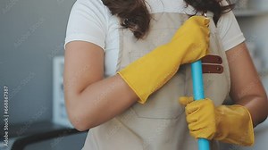 Housewife using vacuum cleaner on the floor. Wearing an apron to clean the living room at house. Young woman is happy to clean home. Maid cleaning service.