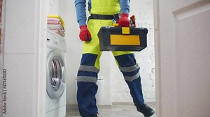 Side view of repairman fixing or installing washing machine in bathroom. Realtime