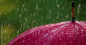 Raindrops falling on red umbrella close-up. Slow motion