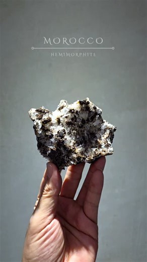 A礦美岩社 on Instagram: "摩洛哥｜異極礦｜hemimorphite 整體為細緻的放射狀晶體群聚，透明至半透明的晶針層層交織，在光線下閃爍出柔亮而清澈的光感。 晶體自然生長於深色母岩之上，形成強烈卻和諧的對比——輕盈與厚重、純淨與原始，同時存在。 異極礦最迷人的地方，在於它的「方向感」。 晶體向外擴散、向內匯聚，像是一種不急不躁、卻持續流動的能量狀態。 近看可見晶針細長、排列自然，沒有過度修飾的痕跡，每一個角度都保留了礦物最真實的樣子。 ◆ Size｜154×54×40mm ◆ Weight ｜385g ◆ Price｜$ 4,200，附專屬訂製壓克力底座 #morocco #hemimorphite #異極礦 #礦物收藏 #A礦美岩社 aw_stones_tw"