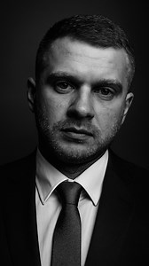 B&W portrait ChatGPT photo idea. P.5 Your thoughts? Create a high-end black and white portrait using my selfie. The face must remain exactly as in on my original selfie — no editing, no retouching, no smoothing. I’m wearing the business suits. Preserve every facial detail and texture for a raw, authentic look. The lighting should be dramatic and studio-quality, using strong contrast and shadows to sculpt the features. Use a clean, blurred studio-style background with soft gradients or subtle tex