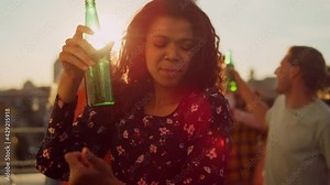 Afro woman enjoying party with beer outdoors. African girl dancing at party.