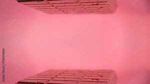 Close-up a milk ruby chocolate bar with chunks of nuts almonds and strawberry, displayed against a pink background is placed on a reflective surface, creating a mirrored image of itself