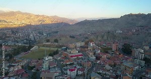 Cable cars travel across La Paz, Bolivia in a scenic, sunset aerial view of the city.