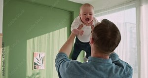 Exuberant Baby Laughing While Being Lifted High by Father Indoors