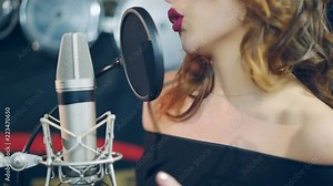 Professional musician recording new song or album in studio. Woman singing in the recording studio.