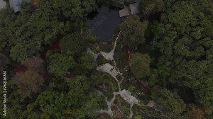 High flyover of a tree covered path and botanical gardens near Malibu horse stables.