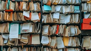Organizing a chaotic filing cabinet filled with documents and folders in a cluttered office space