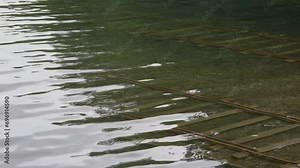 Water ripples over submerged tracks at boat loading dock on lake