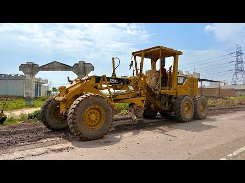 A grader machine is laying gravel on the road.