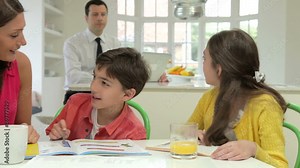 Mother Helping Children With Homework As Father Uses Laptop