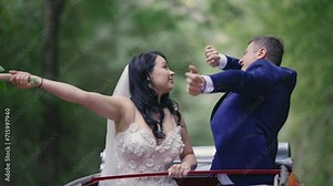 Just married newlywed wedding couple, a party dancing bride and groom are driving in convertible retro car on a country road for honeymoon after the ceremony, slow motioon. The best day and marriage.