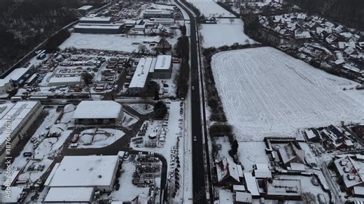 Aerial Birds Eye shot over intersection road with traffic on industrial area of american town. Snowy roofs of buildings and suburbs neighborhood in U.S Top down flyover.