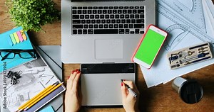 top view of female designer drawing sketches on graphic tablet closeup top view smartphone green screen chromakey laptop keyboard art space business design freelance mockup text content sketch app Stock Video