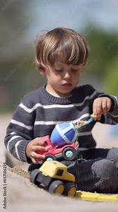 Outdoor Scene Of Young Boy Loading Toy Truck With Sand At Playground In Fun-Filled Activity Stock Video