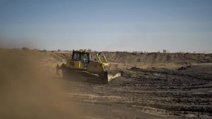 Bulldozer moves pile of soil creating smooth surface for building site. Equipment easily pushes ground preparing area for installing pipelines