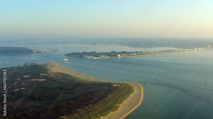 A sweeping aerial shot of Poole Harbour, Sandbanks, Brownsea Island and Studland beach at golden hour with calm peaceful sea