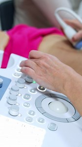 Ultrasound machine is used to check up the pregnancy development. Doctor moves the device by the belly of blonde woman. Vertical video | Premium Stock Video Footage